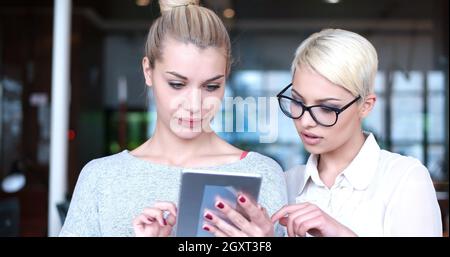 Business Women Using Digital Tablet in Busy Office Stock Photo