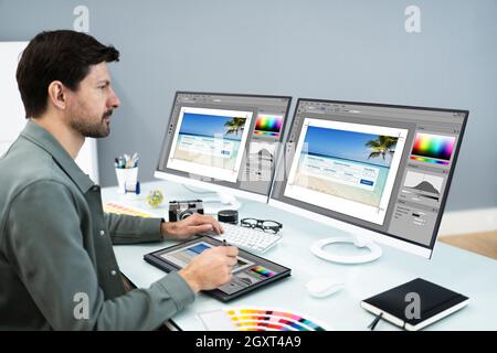 Designer And Photographer Using Multiple Computer Screens Stock Photo