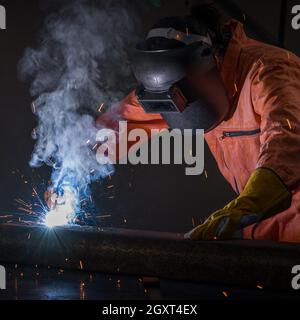 Metal industry worker are welding steel sheets for real estate project received. Sparkler on black background, close-up. Heavy work in factory. Stock Photo