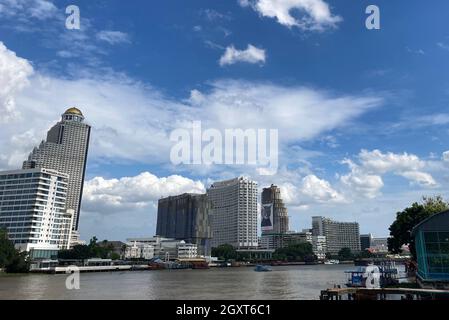 12 September 2021, Thailand, Bangkok: View of the skyline at the Chao Phraya River with the Mandarin Oriental Hotel (l) and State Tower with its gold dome and the poster-covered Sathorn Unique Tower (r). A famous scene from the movie 'Hangover 2' was filmed in the Sky Bar of the State Tower. With the Sathorn Unique Tower, the buildings were meant to be twin towers. The Sathorn Unique Tower is a ruined building, an unfinished 'Ghost Tower'. Many believe in a curse - because there are scary stories about the Lost Place. (to dpa 'Like a post-apocalyptic film set': The ghost tower of Bangkok') Pho Stock Photo