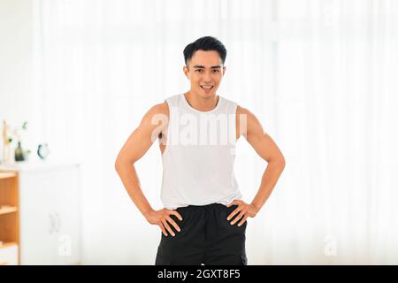 Happy Asian young man Doing Exercises at Home Stock Photo