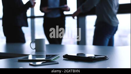 Devices on table with business people in background in modern office building Stock Photo