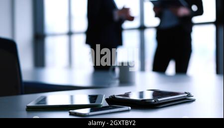 Devices on table with business people in background in modern office building Stock Photo