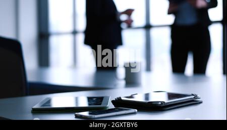 Devices on table with business people in background in modern office building Stock Photo