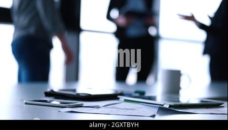 Devices on table with business people in background in modern office building Stock Photo