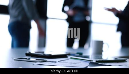 Devices on table with business people in background in modern office building Stock Photo