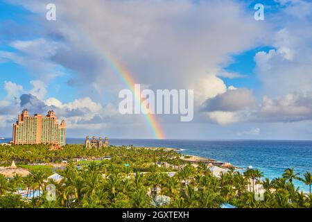 Rainbow over caribbean ocean above island resort covered in palm trees Stock Photo