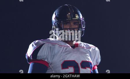 portrait of confident American football players holding ball while standing on field at night Stock Photo