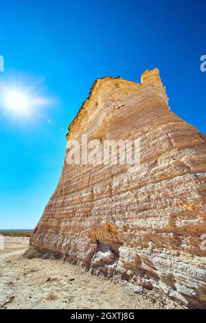 Pillar of white rock in desert with sun and blue sky Stock Photo