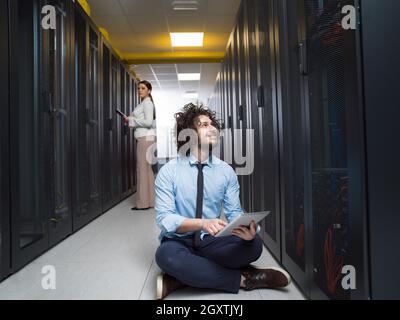 Team of young technicians working together on servers at the data center using tablet computers Stock Photo