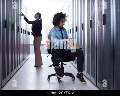 Team of young technicians working together on servers at the data center using laptop computer Stock Photo