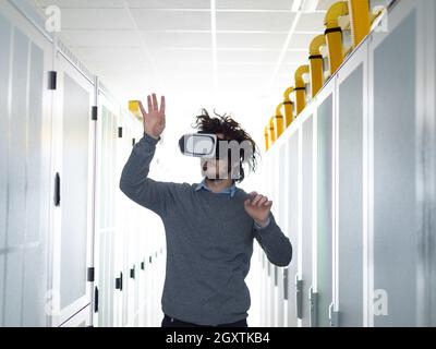 young IT engeneer using virtual reality headset over server room background Stock Photo