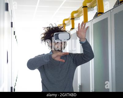 young IT engeneer using virtual reality headset over server room background Stock Photo