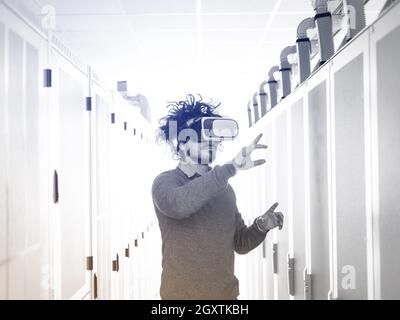 young IT engeneer using virtual reality headset over server room background Stock Photo