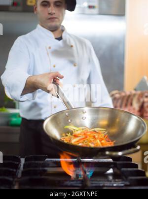 Chef cooking and doing flambe on food in restaurant kitchen Stock Photo