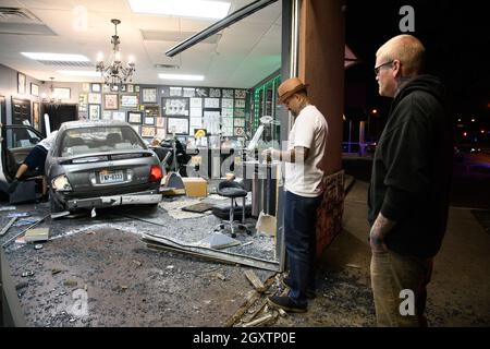 October 5, 2021: A car slammed into the Stainless Studios - Custom Tattoo Parlor in Dallas TX after being struck by another car, destroying a customer sitting area and tattoo station.None of the shop's employees or the occupants of the car were injured. The shop manager said that if a customer had not cancelled her appointment for this evening, they would have been sitting in that station when the vehicle struck.The other car fled the scene, minus a bumper, and is being sought by the Dallas Police Department. Parlor employees look over the damage caused by a car slamming into their ta Stock Photo