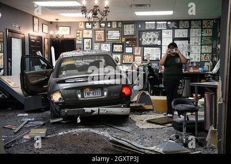 October 5, 2021: A car slammed into the Stainless Studios - Custom Tattoo Parlor in Dallas TX after being struck by another car, destroying a customer sitting area and tattoo station.None of the shop's employees or the occupants of the car were injured. The shop manager said that if a customer had not cancelled her appointment for this evening, they would have been sitting in that station when the vehicle struck.The other car fled the scene, minus a bumper, and is being sought by the Dallas Police Department. One of the vehicle's occupants documents the damages caused by the car. (Cre Stock Photo