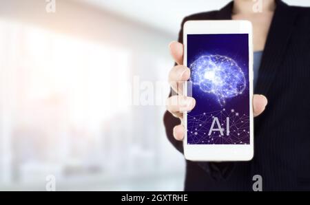 The modern concept of the cyberbrain. Hand hold white smartphone with digital hologram Artificial Brain intelligence sign on light blurred background. Stock Photo