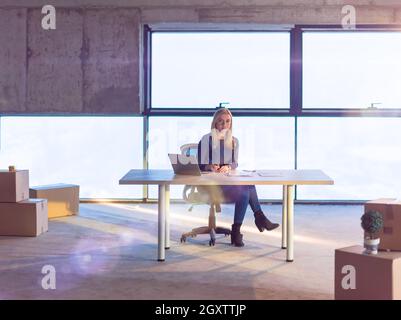 portrait of young female architect on construction site checking documents and business workflow using laptop computer with sunlight through windows i Stock Photo