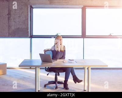 portrait of young female architect on construction site checking documents and business workflow using laptop computer with sunlight through windows i Stock Photo