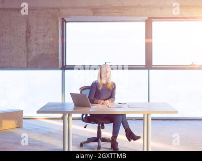 portrait of young female architect on construction site checking documents and business workflow using laptop computer with sunlight through windows i Stock Photo