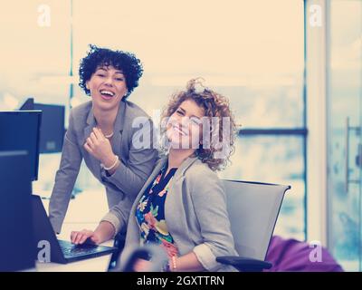 group of young female software developers using laptop and desktop computers while writing programming code at modern creative startup office Stock Photo