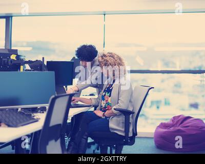 group of young female software developers using laptop and desktop computers while writing programming code at modern creative startup office Stock Photo