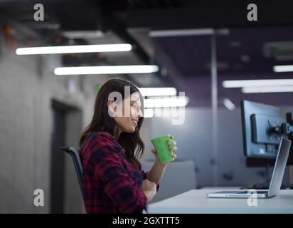 young female software developer using laptop computer while writing programming code at modern creative startup office Stock Photo