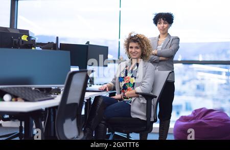 group of young female software developers using laptop and desktop computers while writing programming code at modern creative startup office Stock Photo