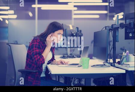 young female software developer using laptop computer while writing programming code at modern creative startup office Stock Photo