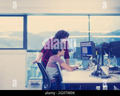 two young male software developers using laptop and desktop computer while writing programming code at modern creative startup office Stock Photo