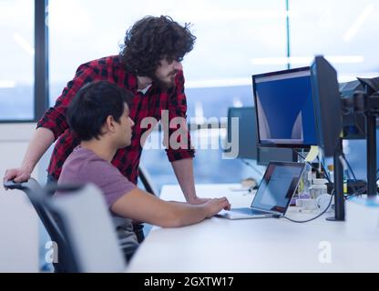 two young male software developers using laptop and desktop computer while writing programming code at modern creative startup office Stock Photo