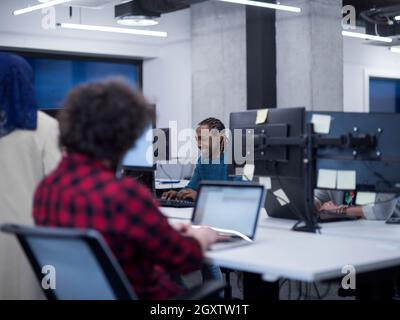 young multiethnics business team of software developers working together using laptop and desktop computers while writing programming code at modern s Stock Photo