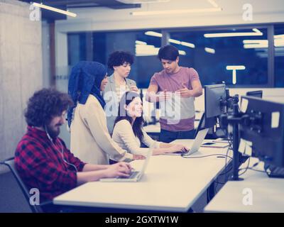 young multiethnics business team of software developers working together using laptop and desktop computers while writing programming code at modern s Stock Photo