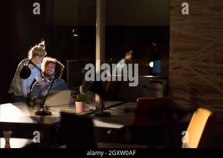 Two young designers are working on a new project in the night office using modern technology Stock Photo