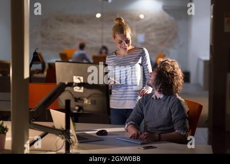 Two young designers are working on a new project in the night office using modern technology Stock Photo