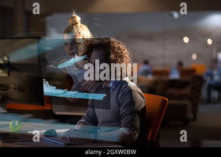 Two young designers are working on a new project in the night office using modern technology Stock Photo