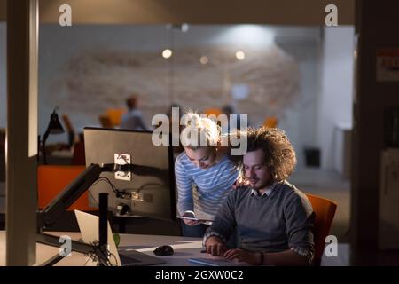 Two young designers are working on a new project in the night office using modern technology Stock Photo