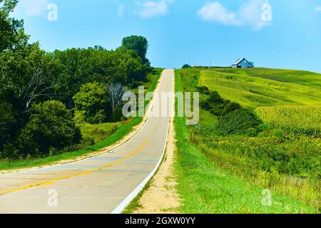 Empty old road through hills and cornfields with barn Stock Photo