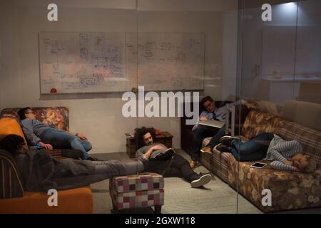 group of young casual software developer sleeping on  sofa during a work break in creative startup office Stock Photo