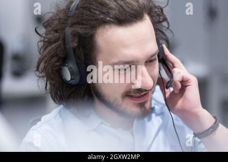 young smiling male call centre operator doing his job with a headset Stock Photo