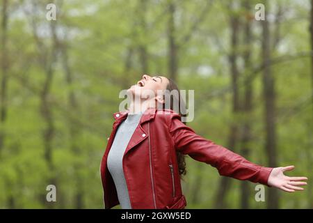 Excited woman in red spreding arms in a forest on vacation Stock Photo ...