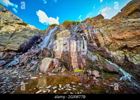 Detail of waterfall over mossy rocks in rocky mountains Stock Photo