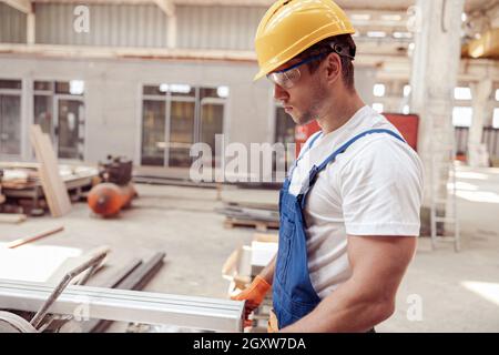 Handsome male worker using sawing machine in workshop Stock Photo