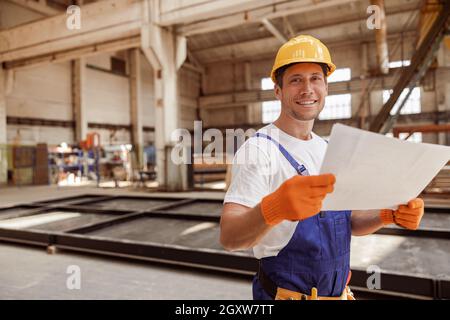 Cheerful builder studying architectural plan at construction site Stock Photo