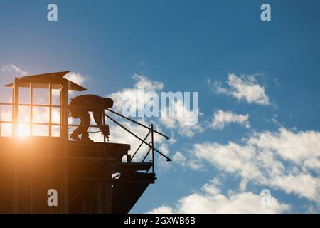 Construction Workers Silhouette on Roof of Building. Stock Photo