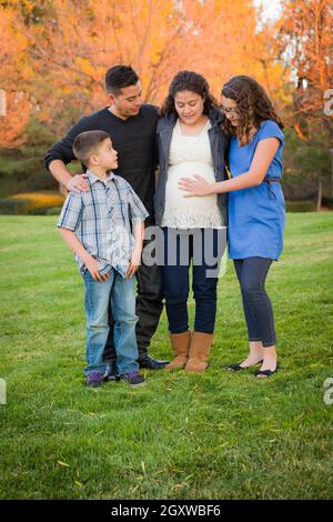Hispanic Pregnant Family Portrait Against Fall Colored Trees. Stock Photo