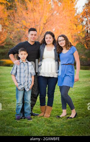 Hispanic Pregnant Family Portrait Against Fall Colored Trees Stock Photo