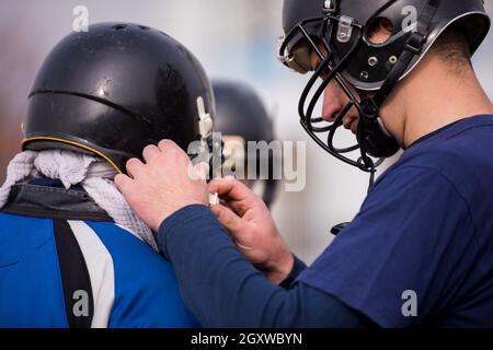closeup shot of American football player checking helmets at field Stock Photo