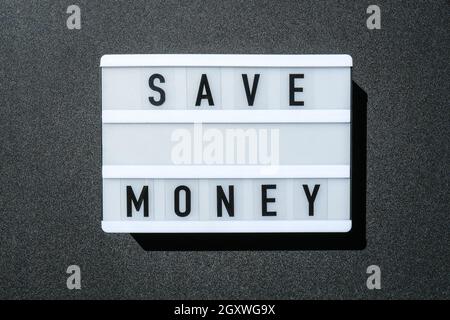Lightbox board on a black background with the words SAVE MONEY in black letters. Stock Photo